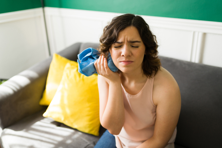 Woman in pain holding an ice pack to her jaw
